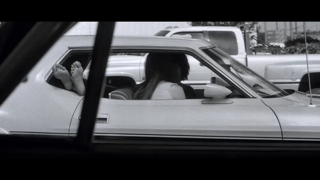Rosario Dawson resting with her feet outside a car window.