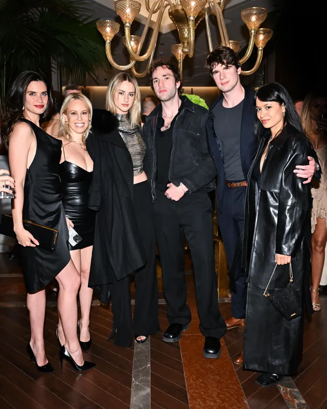 Grace Van Patten posing with a group in a black outfit and heels.