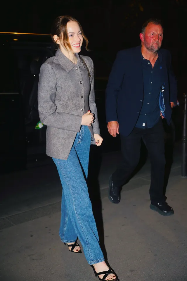 Emma Stone walking outside in jeans and black heeled sandals.