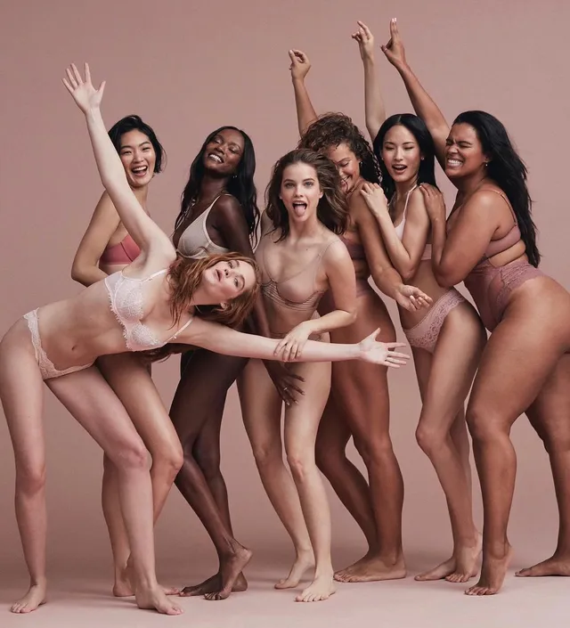 Barbara Palvin posing barefoot with other models in a pink studio.