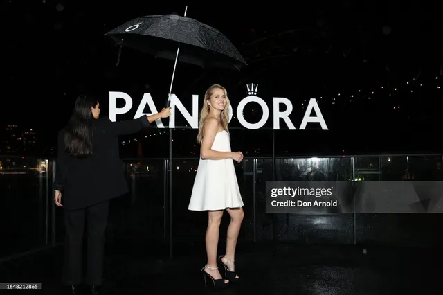 Teresa Palmer posing beneath an umbrella in a white dress.