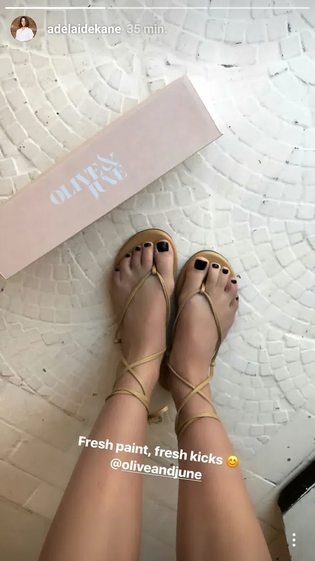 Adelaide Kane a close-up of gold lace-up flat sandals.