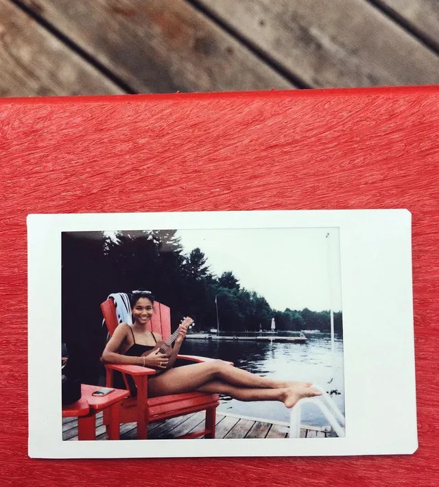 Greta Onieogou shown in a printed photograph reclining by a lake with bare feet.