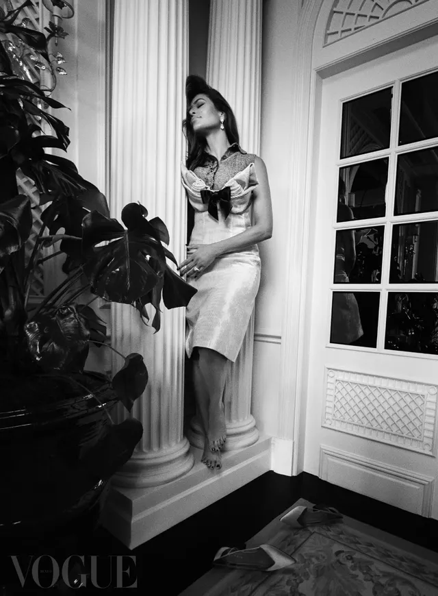 Eva Mendes standing beside a window in a monochrome fashion portrait.