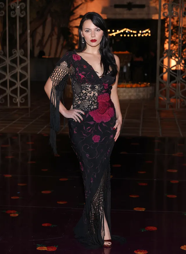Dafne Keen standing outdoors in a patterned dress and heels.