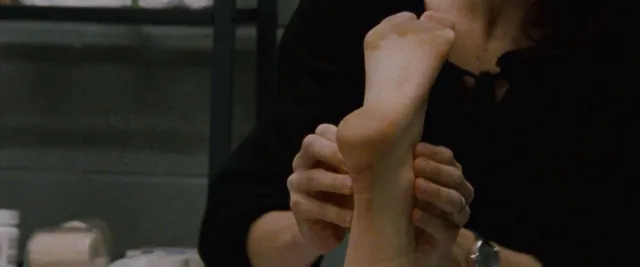 Natalie Portman holding a bare foot in a close-up screen scene.