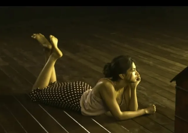 Deepika Padukone lying barefoot on a wooden floor in a polka-dot skirt.