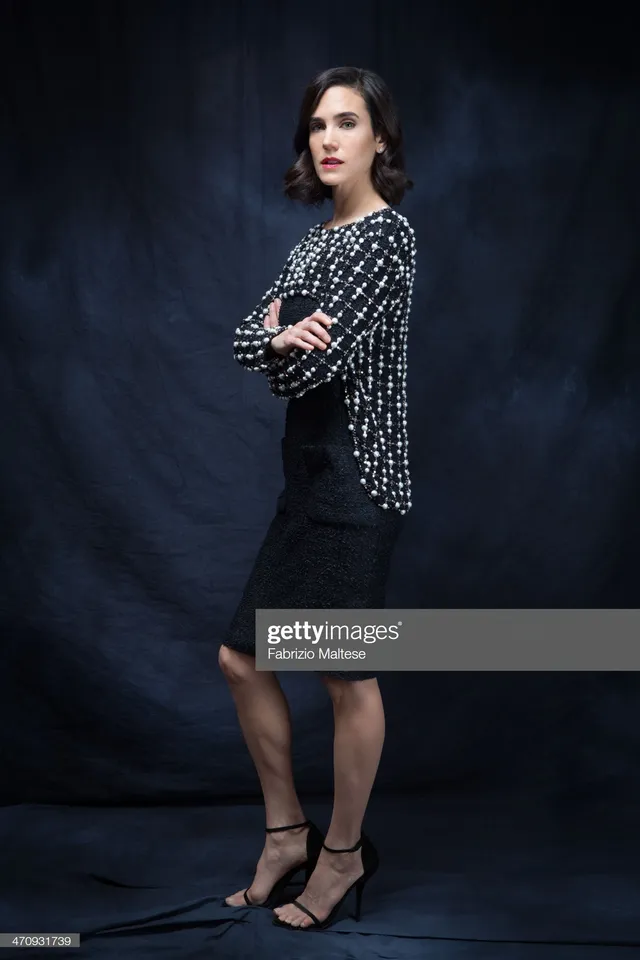 Jennifer Connelly posing for a portrait in a patterned blouse and dark skirt.