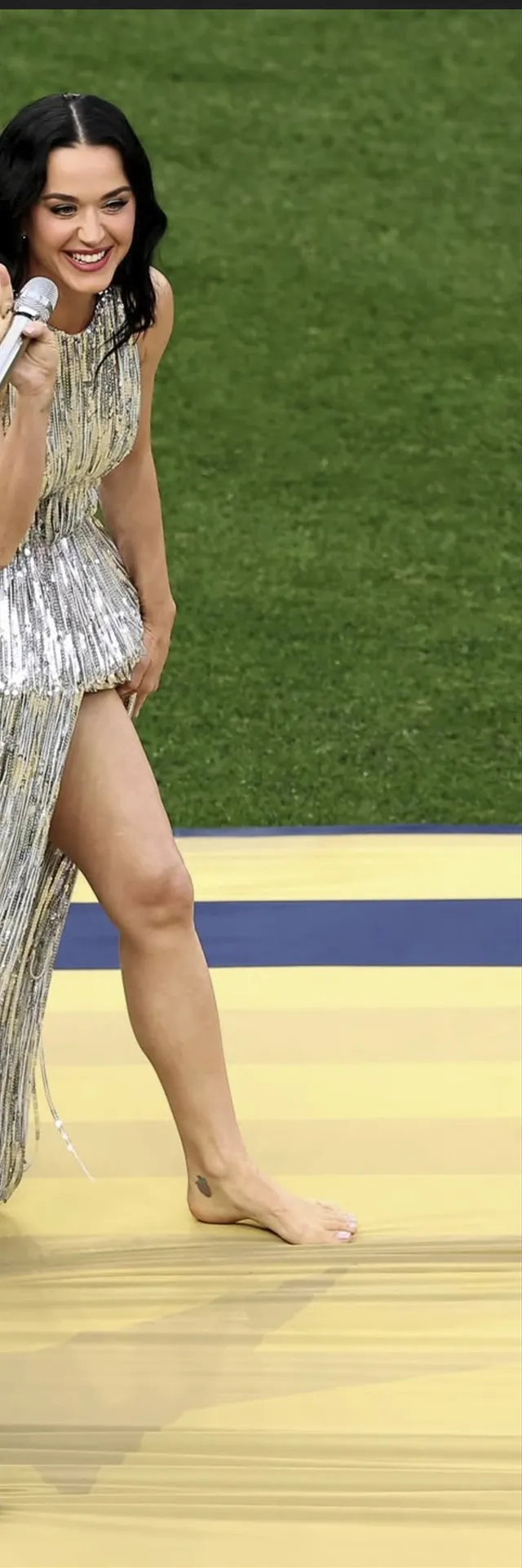 Katy Perry performing barefoot in a metallic outfit.