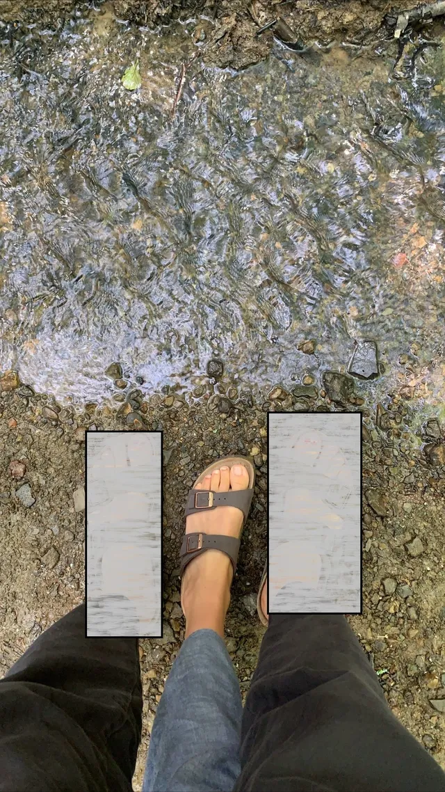 Anya Chalotra showing a flat sandal while standing on uneven ground.