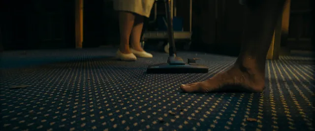 Ester Expósito standing barefoot beside companions during a hallway scene.