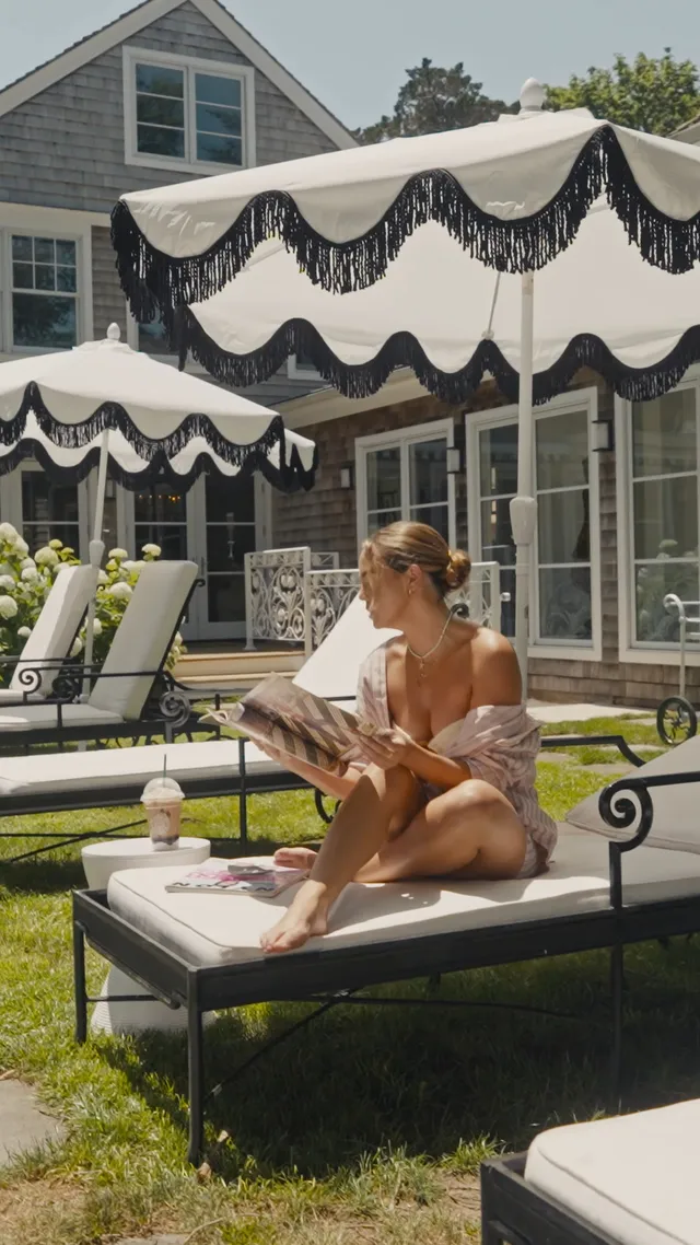 Bailee Madison reading barefoot on an outdoor lounger.