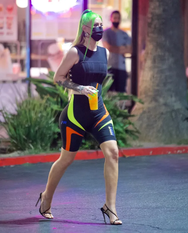 Iggy Azalea walking outdoors in a black outfit and strappy heels.