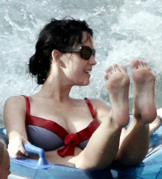 Katy Perry floating in water with bare soles raised.