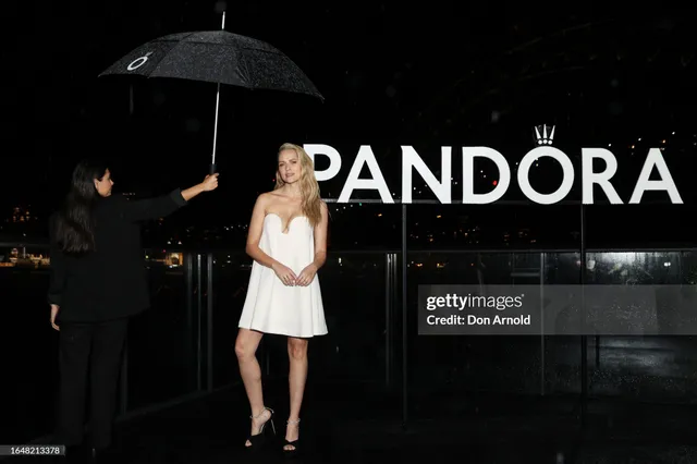 Teresa Palmer standing at an event beneath an umbrella.