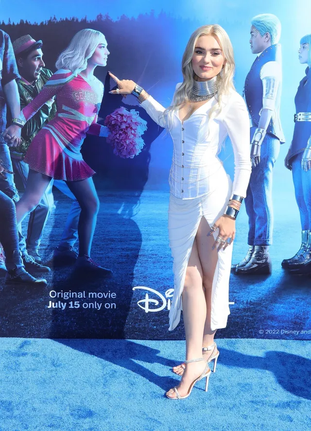 Meg Donnelly posing in a white dress and light heels at a Zombies 3 event.