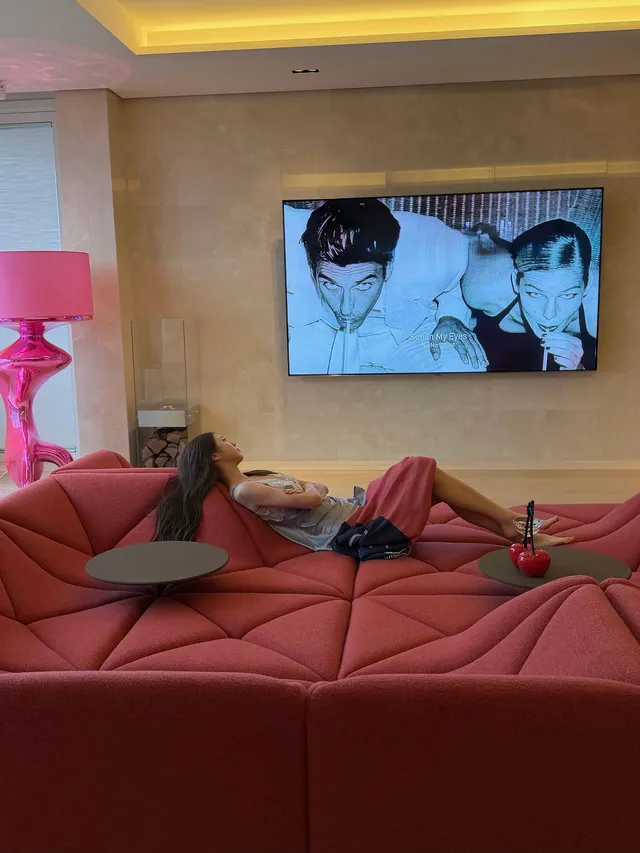 Jang Wonyoung reclining barefoot on a red sofa.
