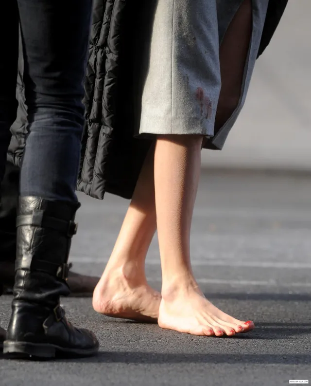 Angelina Jolie a street detail of bare feet beneath a grey coat.