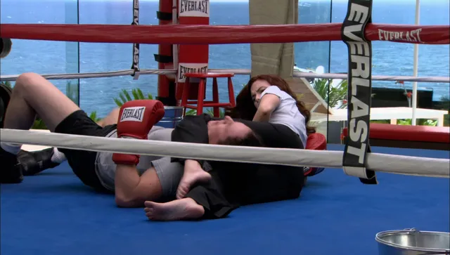 Scarlett Johansson sitting beside a companion in a boxing ring.