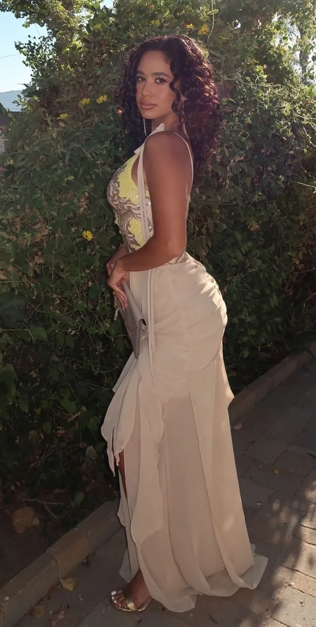 Emily Tosta wearing a pale gown and heels outdoors.