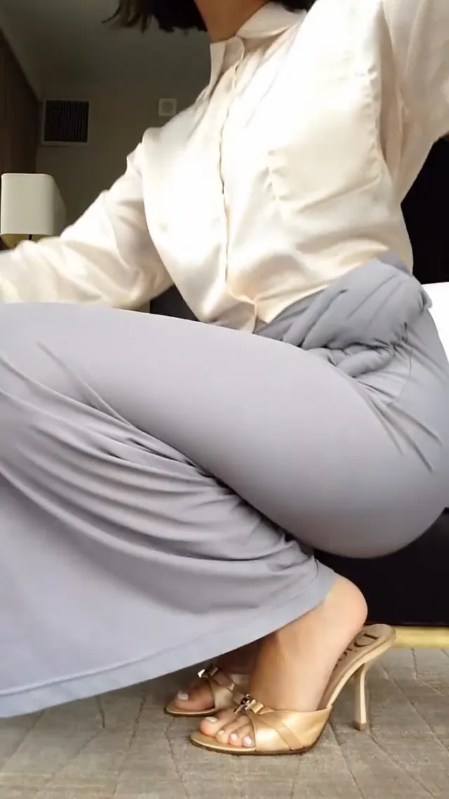 Ariana Greenblatt crouching in a pale blouse and metallic heels.