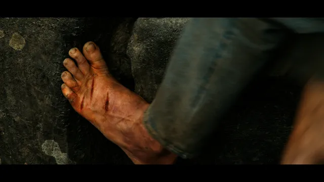 Charlize Theron a close screen detail of an injured bare foot on stone.