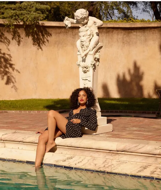 Tessa Thompson sitting at the edge of a swimming pool.