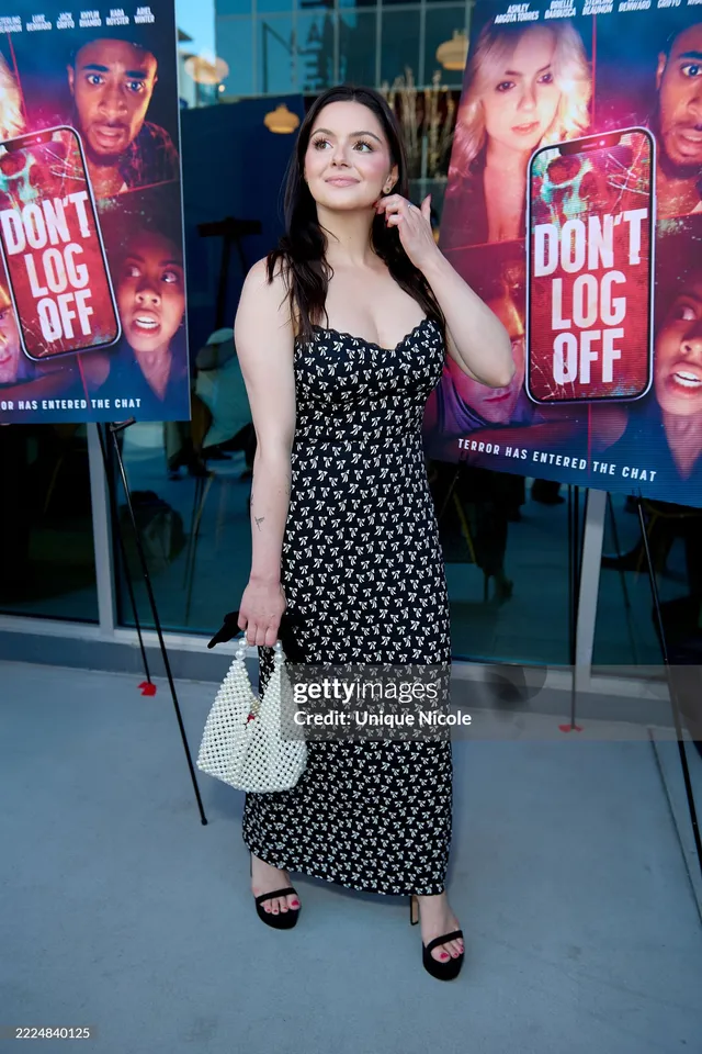 Ariel Winter standing beside a film poster in a patterned dress.