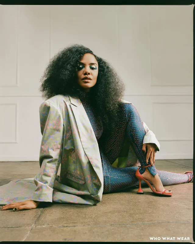 Tessa Thompson sitting on a carpet in a studio fashion portrait.