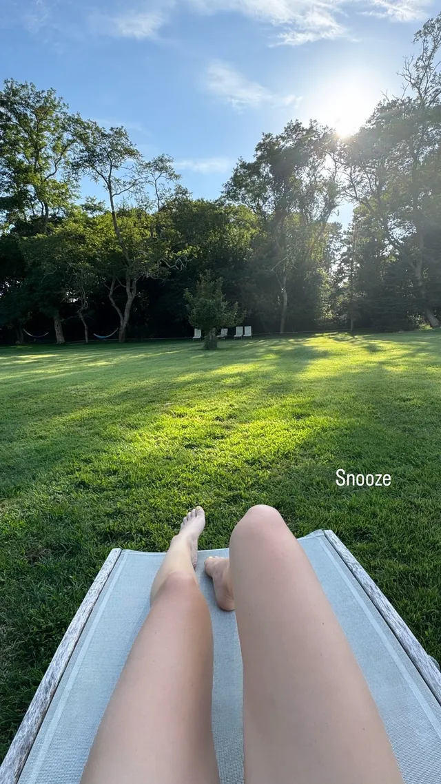 Brec Bassinger reclining barefoot outdoors on a garden lounger.