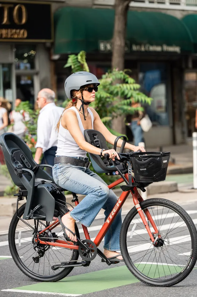 Jennifer Lawrence cycling outdoors in jeans and black sandals.