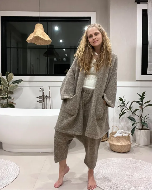 Teresa Palmer standing indoors in a loose casual outfit.