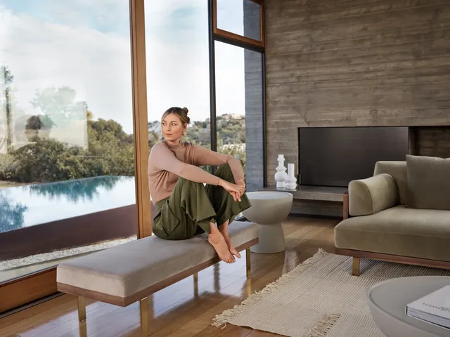 Maria Sharapova sitting barefoot on a bench in green trousers.