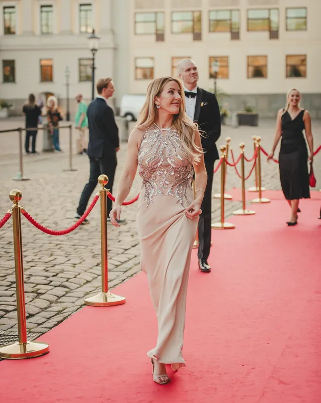 Ellie Goulding walking on a red carpet in a pale gown and heels.