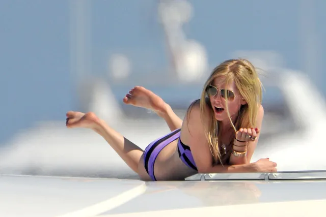Avril Lavigne lying on a boat with bare feet raised.