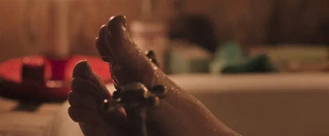 Gemma Arterton raising a bare foot in a dramatic screen scene.