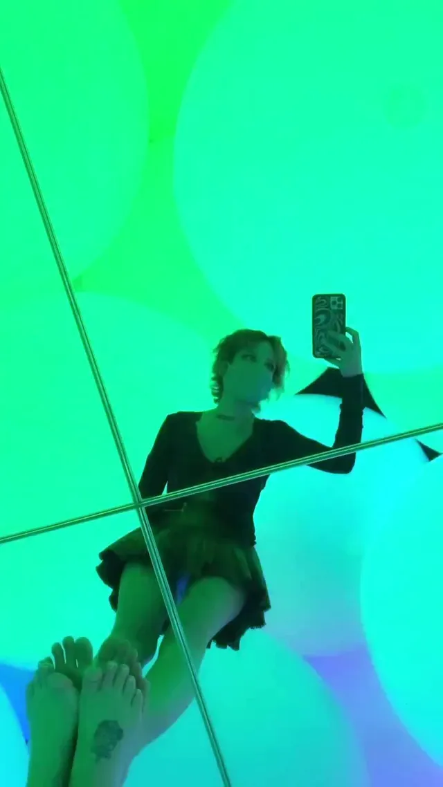 Halsey a green-lit mirror portrait with bare feet visible.