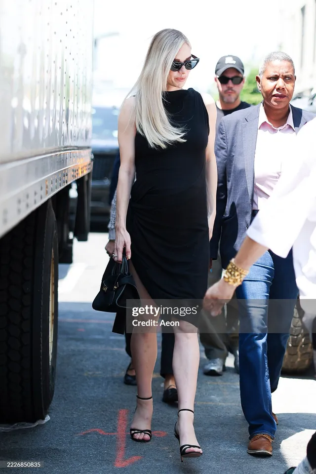 Vanessa Kirby walking beside other people wearing a black dress and heels.