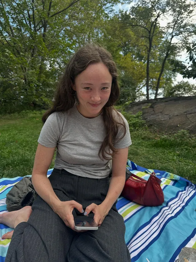 Havana Rose Liu sitting barefoot on a picnic blanket.