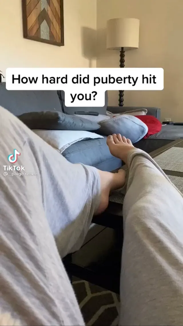 Paige Spiranac resting her bare feet on a sofa in a casual indoor photograph.