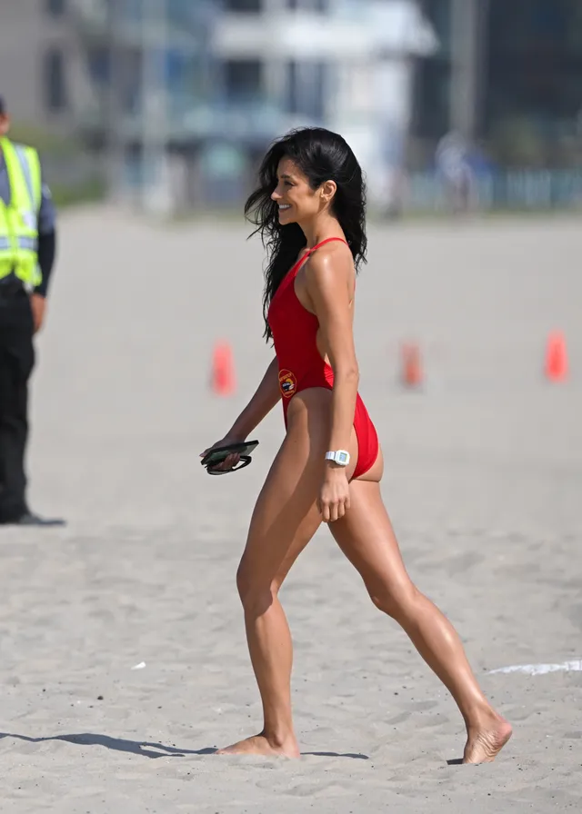 Shay Mitchell walking on a beach in red swimwear.