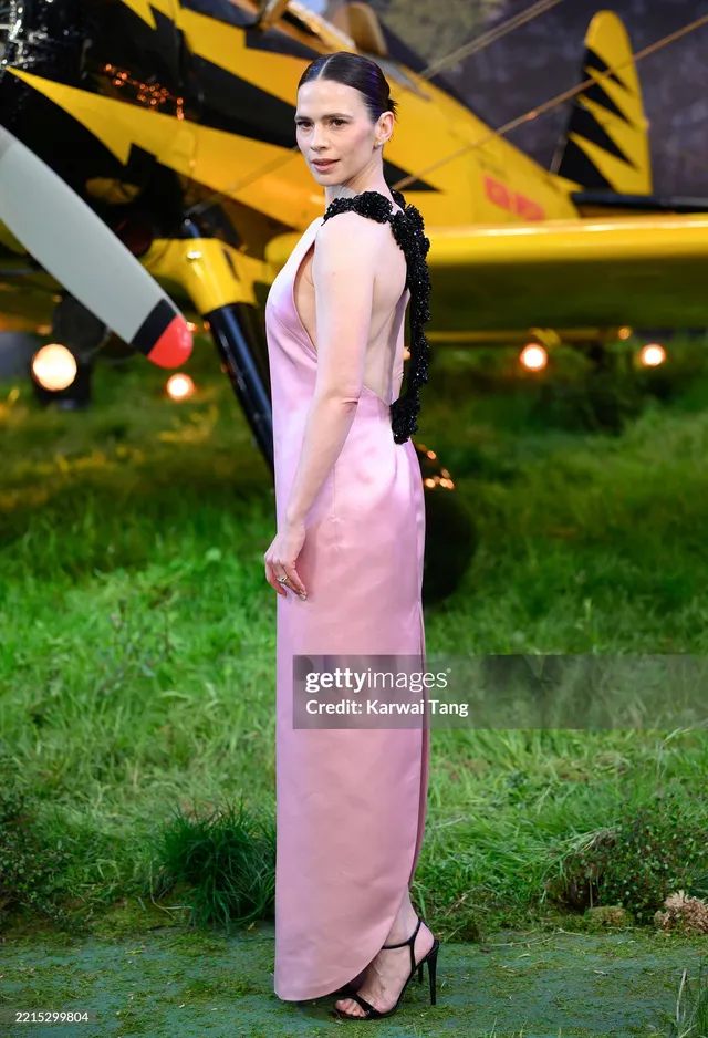 Hayley Atwell turning toward cameras in a pink gown.