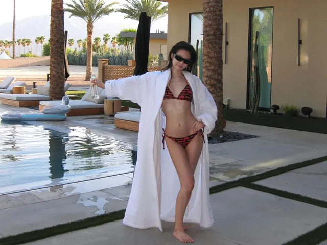 Jennie Kim standing barefoot beside a swimming pool in a pale robe.