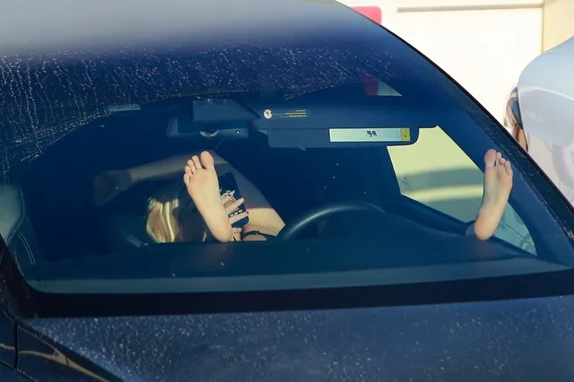 Ariel Winter resting her bare feet inside a parked car.