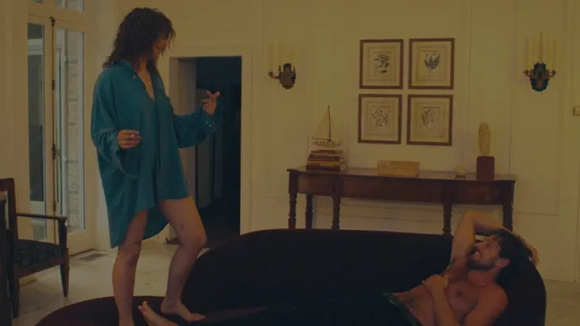 Odessa A'zion standing barefoot beside a sofa in a scene.