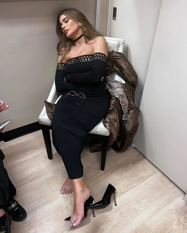 Sofía Vergara sitting with one bare foot beside a black high heel.