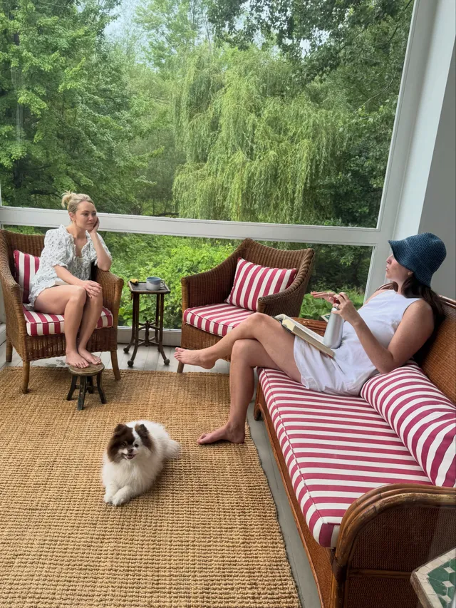 AnnaSophia Robb relaxing on a porch sofa with a companion and dog.