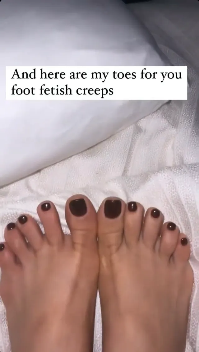 Bebe Rexha showing a dark pedicure in a close-up.
