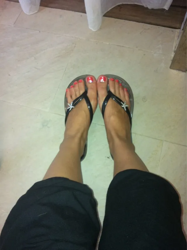 Úrsula Corberó shown from above wearing dark flip-flops.