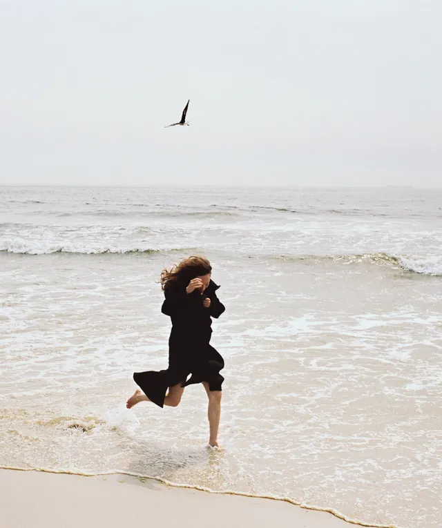 Havana Rose Liu running barefoot through beach water.